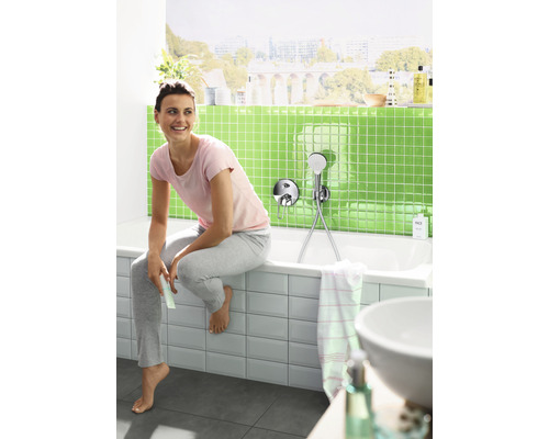 Vrouw zit op de badrand in een badkamer met opbouw-douchegarnituur.