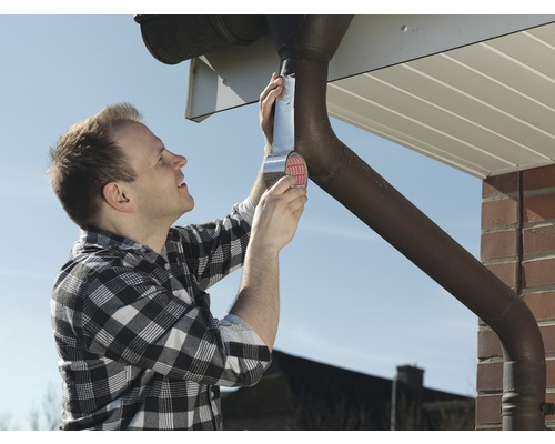 Man repareert een dakgoot met afdichtband.