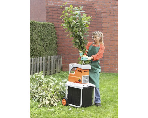 Vrouw bedient een Atika tuinhakselaar voor het versnipperen van takken en groenafval