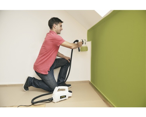 Man schildert muur met verfspuitsysteem