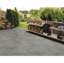 Terras met grijze terrastegels en barbecueplaats in de tuin