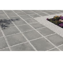 Vierkante betontegels gelegd met siergrind in de tuin.