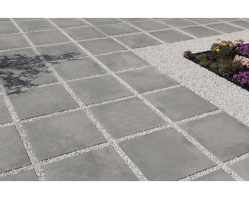 Vierkante betontegels gelegd met siergrind in de tuin.