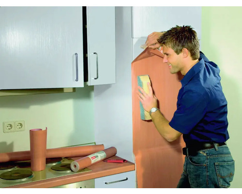 Man brengt meubelfolie aan in een keuken