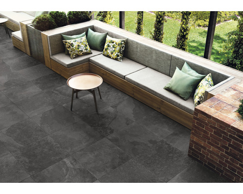 Buitenruimte met grijze vloertegels, zithoek met kussens en kleine tafel