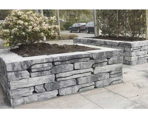 Twee plantenbakken van steen met beplanting buitenshuis