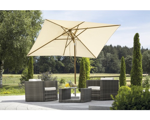 Vierkante parasol boven rotan zitgroep met glazen tafel in de tuin