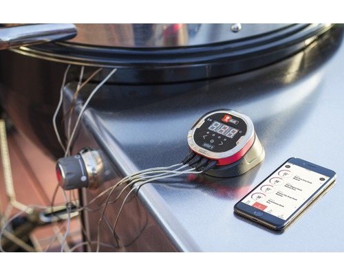 Weber grillthermometer met digitale display en smartphoneverbinding op een barbecue