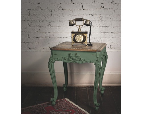 Antieke telefoon op een versierde bijzettafel voor een bakstenen muur