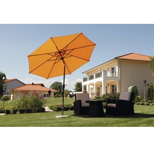 Oranje parasol met tuinmeubelen op een gazon voor een woonhuis.