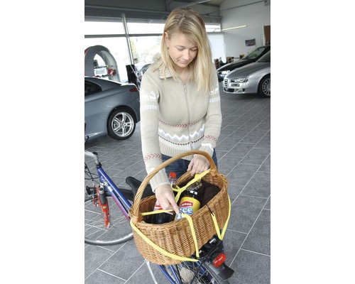 Vrouw bevestigt fietsmand aan fiets voor transport
