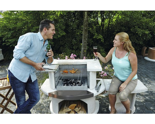 Man en vrouw aan het barbecueën in de tuin met stenen barbecue.