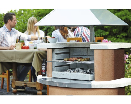 Gemetselde tuingrill met barbecuegerechten, houtskool en Jack Daniel''s barbecuesaus in de tuin met mensen