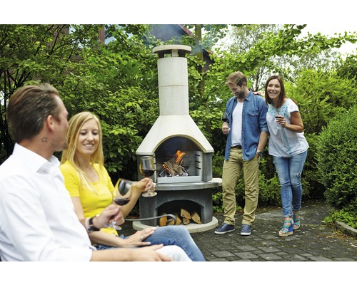 Barbecue met brandend hout en mensen in de tuin.