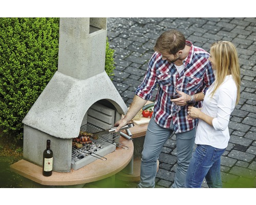 Man en vrouw barbecueën bij een stenen tuingrill met een fles wijn