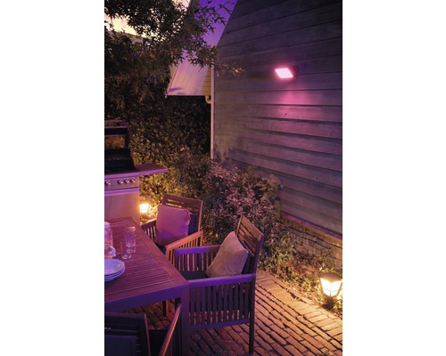 Verlicht terras met houten tafel, stoelen en barbecue