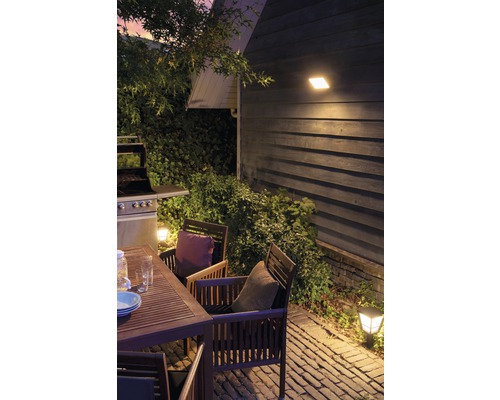 Buitenruimte met tuintafel, stoelen, barbecue en buitenverlichting.
