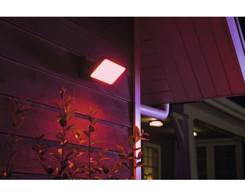 Vierkante led-buitenwandlamp aan huis met begroeiing