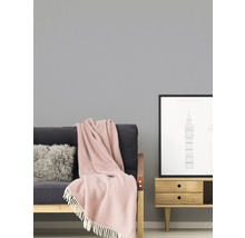 Woonkamer met bank, kussen, deken en bijzettafel met fotolijst