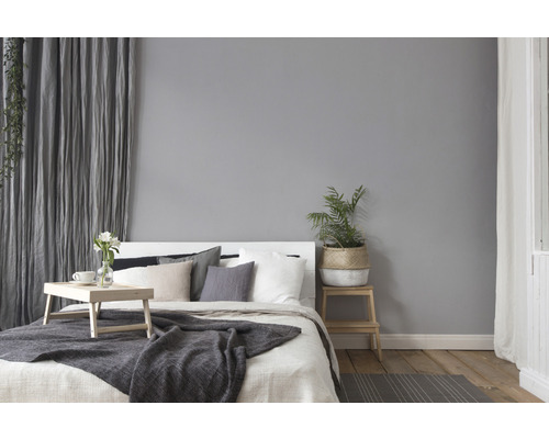 Lichte slaapkamer met bed, kussens, deken, gordijnen en planten