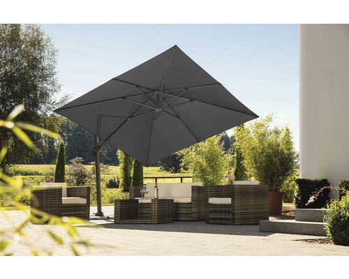 Vierkante zweefparasol boven een rotan zitgroep in de tuin