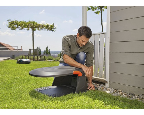 Man installeert een gazonrobot in de tuin