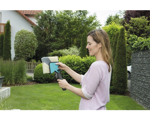 Vrouw houdt een wasborstel in de tuin vast