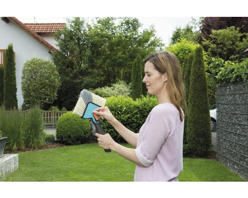 Vrouw houdt borstel vast voor het reinigen van oppervlakken in de tuin