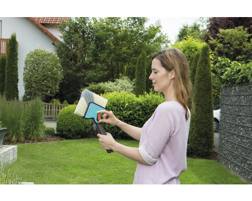 Vrouw bekijkt een oppervlakteborstel in de tuin.