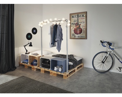 Slaapkamer met palletbed, kledingrek met verlichting en decoratieve kisten