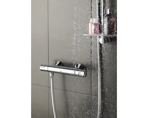 Foto van een douchekraan met doucheslang voor een betegelde achtergrond