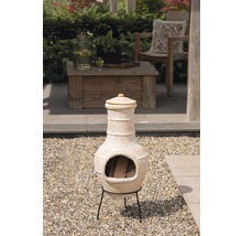 Terraskachel van terracotta op een grindvloer met brandhout erin