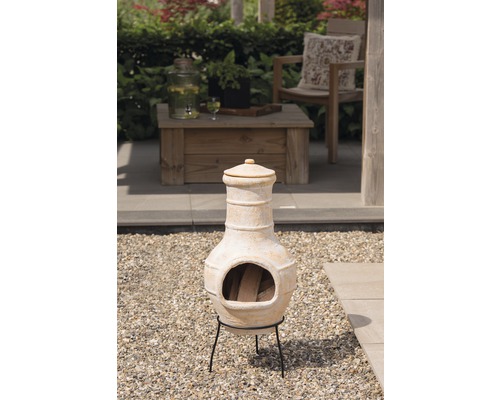 Terraskachel van terracotta op een grindvloer met brandhout erin