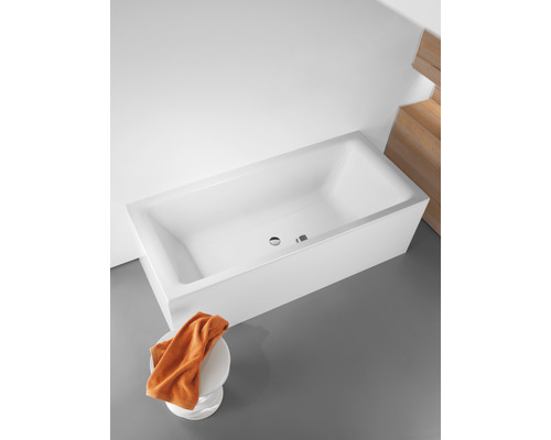 Rechthoekig ligbad van sanitairacryl met overloop en handdoek op een kruk