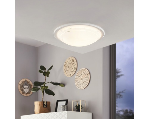 Plafondlamp in woonkamer met decoratieve elementen aan de wand.
