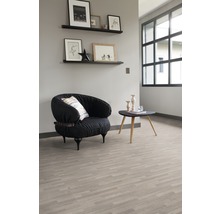 Lichte ruimte met een fauteuil, een tafel en planken aan de muur, die een georganiseerde indruk geeft.