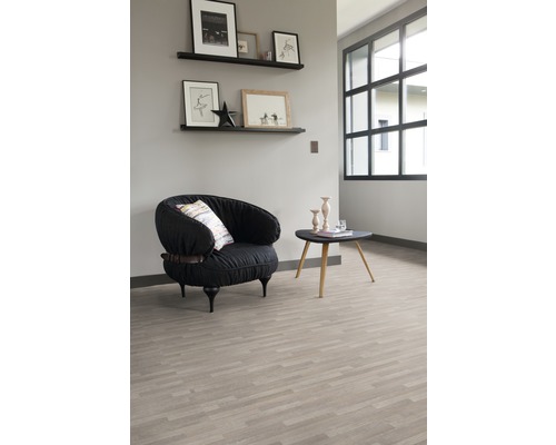 Lichte ruimte met een fauteuil, een tafel en planken aan de muur, die een georganiseerde indruk geeft.