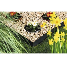 Tuinscene met gazon, stenen, bloemen en een metalen rand voor bloembedden