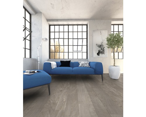 Woonkamer met blauwe bank, staande lamp en houten vloer