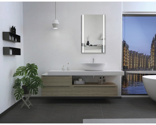 Moderne badkamer met wastafel, verlichte spiegel en ligbad voor een raam