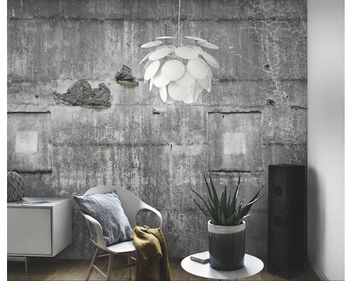 Woonkamer met betonbehang, fauteuil, bijzettafel met plant, luidspreker en hanglamp