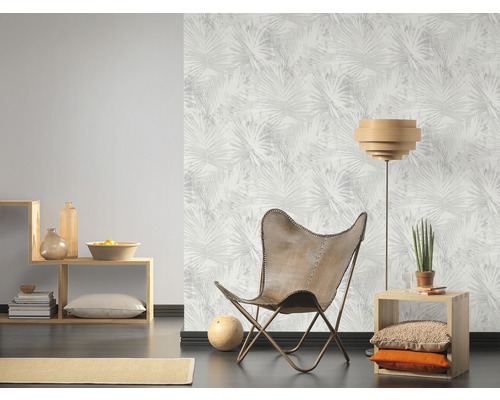 Woonkamer met fauteuil, staande lamp, wandplank en behang met plantenmotief