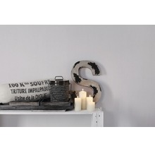 Decoratieve scène met kussen, blik, kaarsen en een letter op een plank