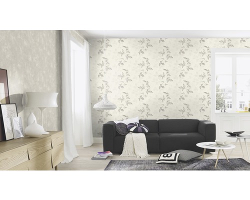 Woonkamer met patroonbehang, bank en houten commode