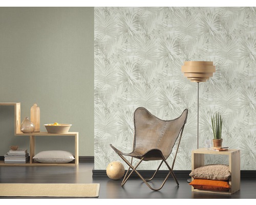 Woonkamer met patroonbehang, fauteuil en rekken.