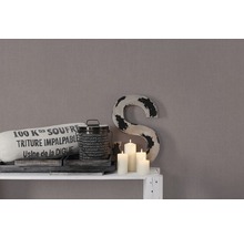 Decoratie met kussen, blik, kaarsen en een grote letter op een plank