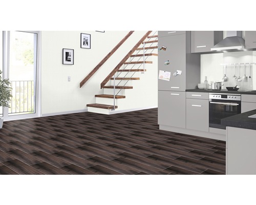 Modern interieur met donkere laminaatvloer, trap met houten treden en grijze keuken.