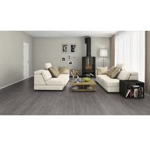 Woonkamer met grijze vloerbedekking, open haard en witte banken.