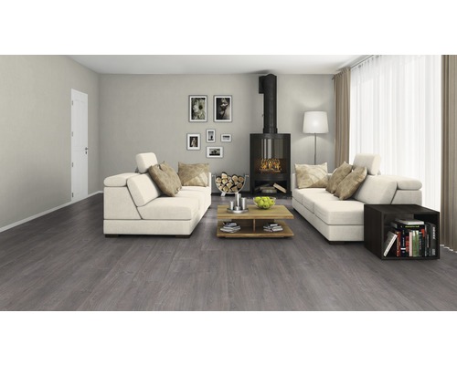 Woonkamer met grijze vloerbedekking, open haard en witte banken.