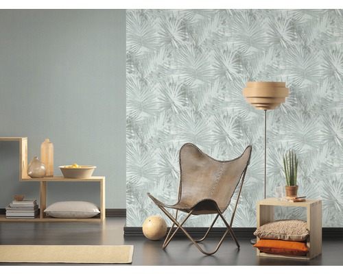 Woonkamer met fauteuil, vloerlamp en behang met bladerpatroon